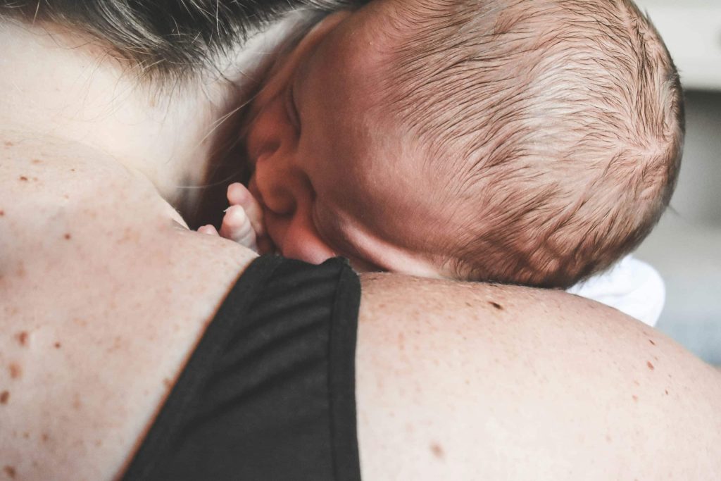 Woman holding her infant in her arms, symbolizing the fourth trimester bonding.