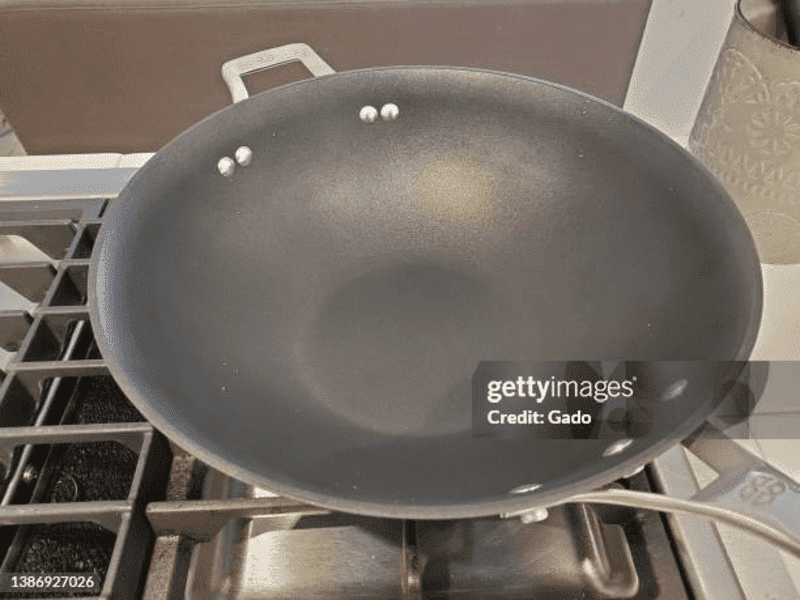 A non-stick cooking wok on a stovetop. If heated too high, non-stick Teflon and other polymer pans can release fumes that cause a respiratory illness called Teflon flu.