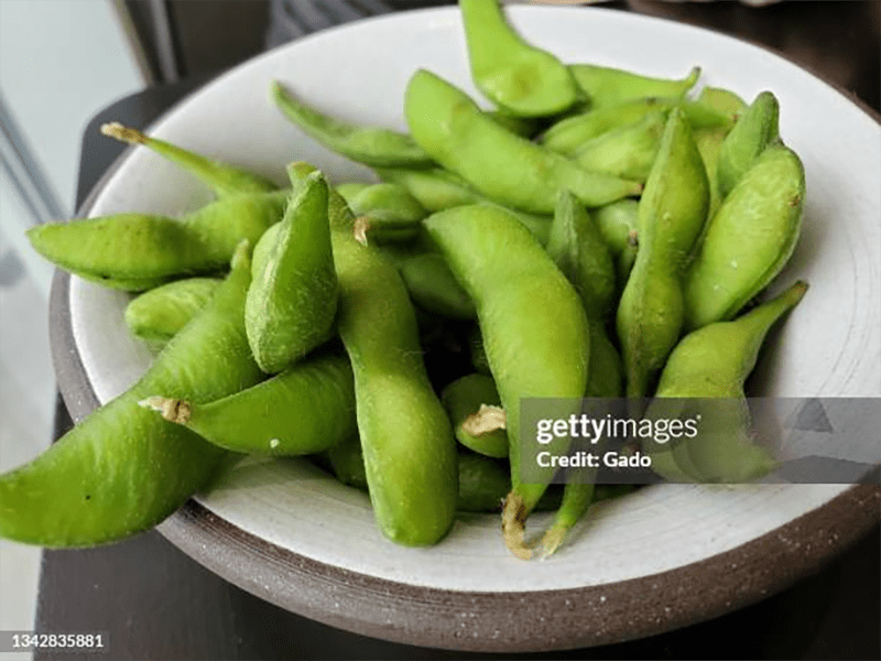 A bowl of edamame, immature green soybeans still inside their pods.