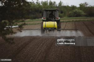 Farmer using a tractor to spray pesticide. The EPA recently issued a pesticide ban on Dacthal.