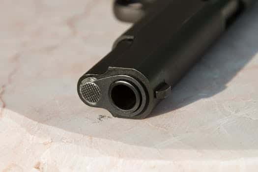 Detailed close-up of a gun barrel resting on a marble surface, highlighting the metal texture.