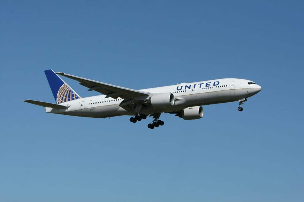A United plane flying against a clear blue sky, showcasing air travel.