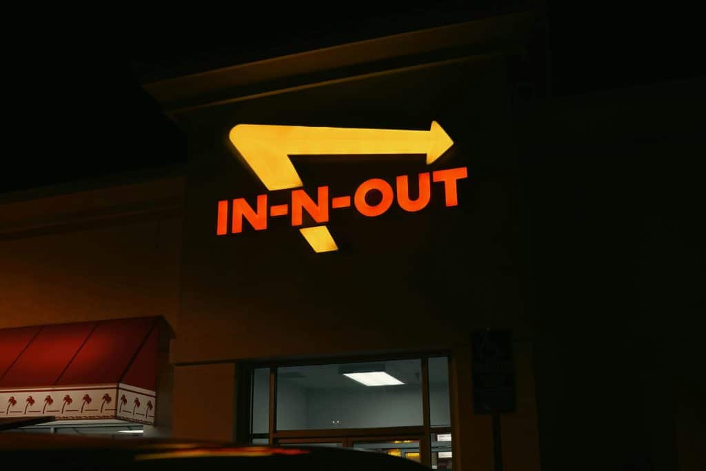Bright neon In-N-Out sign glowing at night outside a restaurant in California.