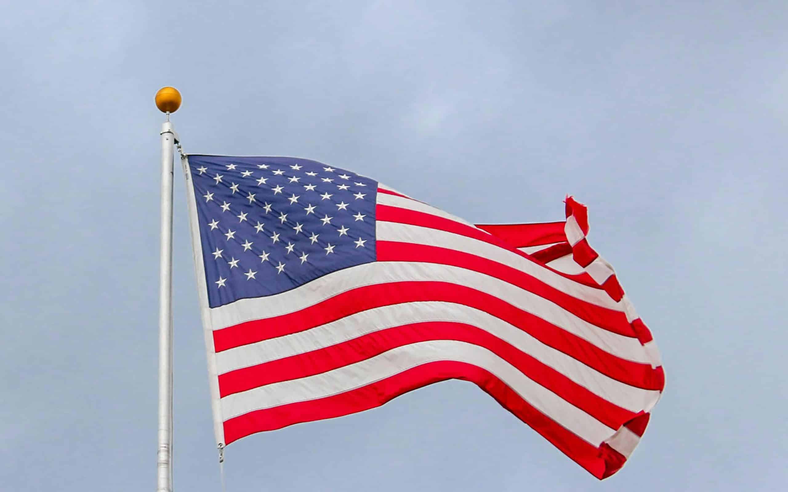 A vibrant image of the American flag waving proudly against a clear blue sky, symbolizing freedom. Memorial Day events