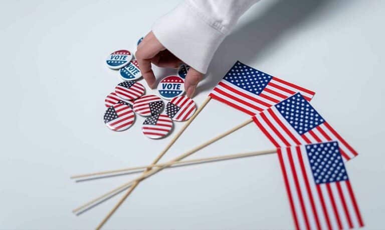 Hand reaching for voting buttons and USA flags, symbolizing patriotism and democratic duty.