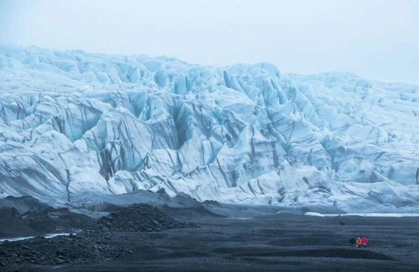 glacier ice sheets pictured in the ocean under grey clouds.