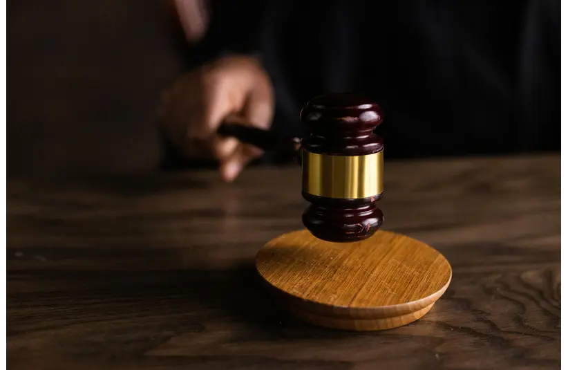 A judge's gavel poised above a wooden block on a desk, suggesting a courtroom setting, conveying authority and decision-making.