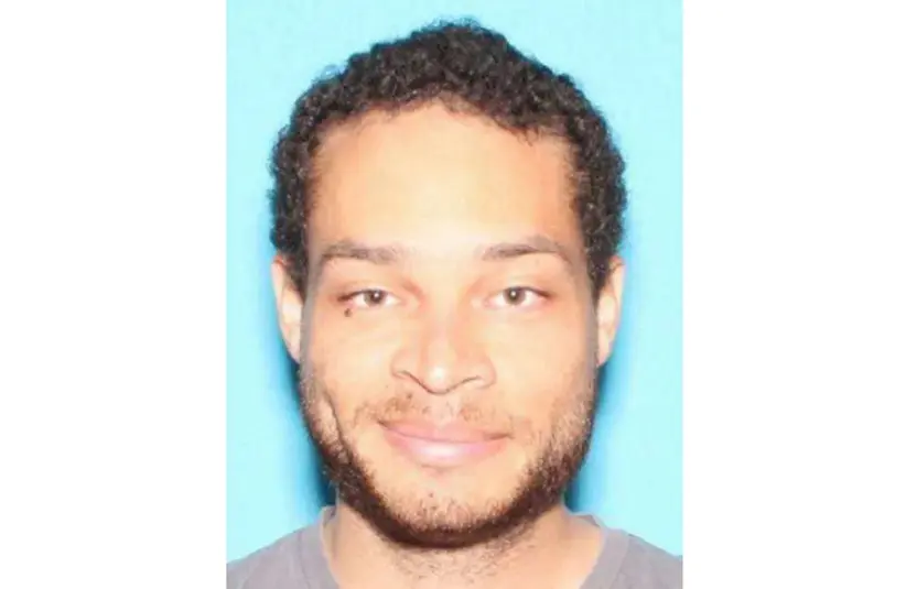 Cole Tomas Allen, a person with short curly hair, light facial hair, and a gentle smile is pictured against a blue background. The image has a warm and relaxed tone.