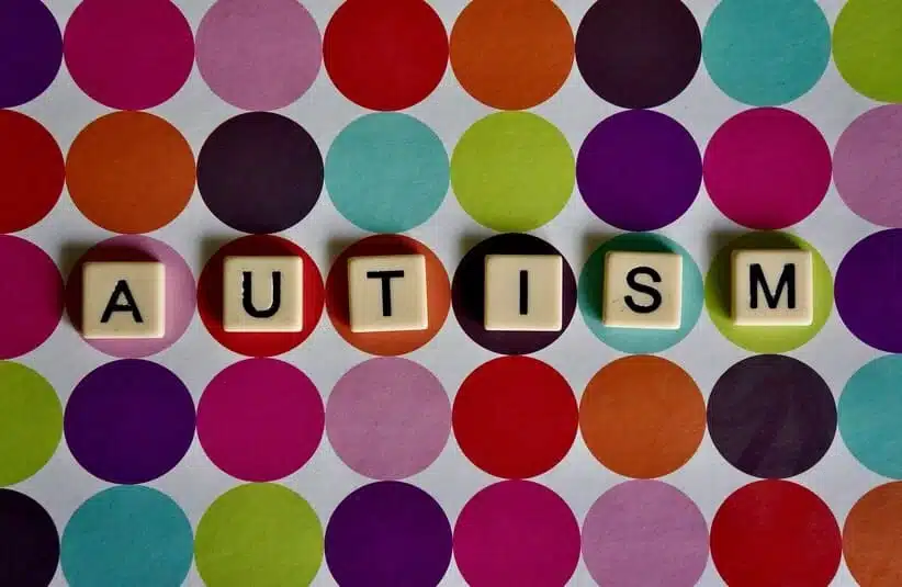 colored circles of letters in the background with a word "autism" spelled out in the center.