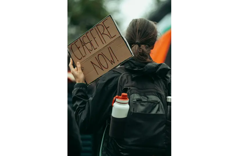 A protester marching with a sign declaring CEASEFIRE NOW!