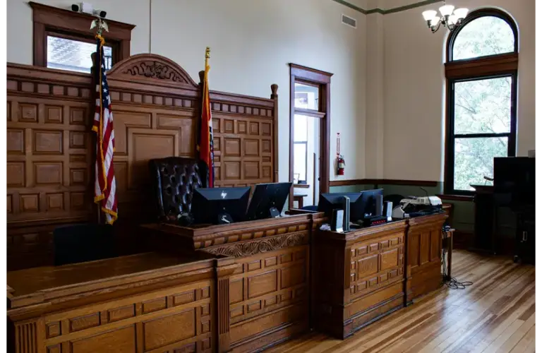 An American Courtroom with American Flags on either side of the Judge's chair, currently not in session.