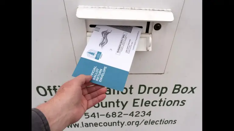 A person inserts an official ballot envelope into a county election drop box. The box displays election office information and contact details. Trump's executive order for mail-in ballots was not struck down.