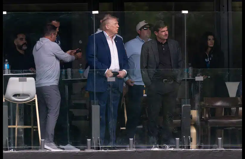 Donald Trump and LIV Golf CEO Scott O'Neil stand in a glass-enclosed balcony, with one person in a blue suit as the focal point. The atmosphere appears tense yet focused.
