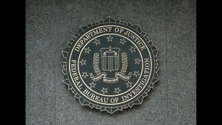 A circular FBI seal mounted on a textured stone wall, featuring a central shield with laurel branches, a red banner reading “Fidelity, Bravery, Integrity,” and outer text identifying the Department of Justice (DOJ) and the Federal Bureau of Investigation. They have removed Jan 6 files.