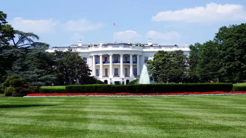 View of the White House North Lawn with lush gardens and a central fountain on a sunny day. A Shooting occurred in the vicinity.