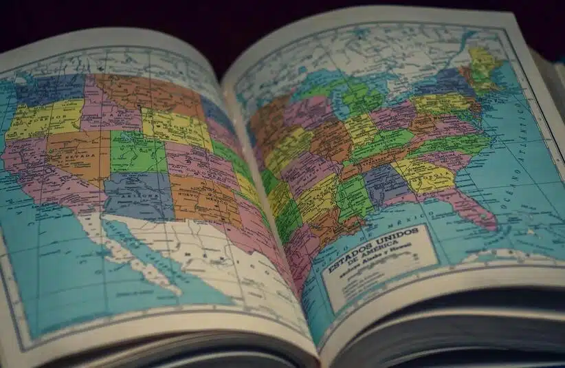 Open atlas showing a map of the United States, highlighting states with vibrant colors.