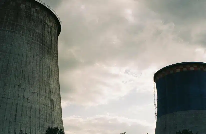 Imposing cooling towers of a nuclear power station under a cloudy sky, showcasing industrial architecture.
