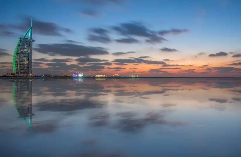 Twilight reflecting on the beach of Dubai's beautiful cityscape, UAE, captures the iconic Burj Al Arab hotel