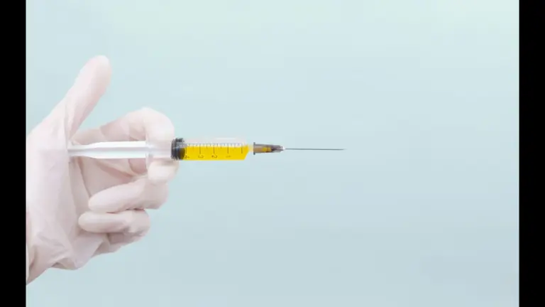A gloved hand holds a syringe filled with yellow liquid against a light blue background, evoking a clinical, sterile, and focused atmosphere. A new vaccine for fentanyl.