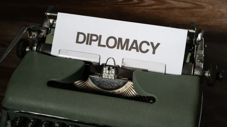 Sheet of paper displaying the word DIPLOMACY in a vintage typewriter. The background is a dark wooden surface.
