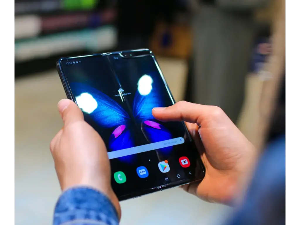 hands holding a foldable smartphone in a close-up shot reveal a vivid butterfly on the screen, highlighting how foldable phones blend tech with visual creativity.