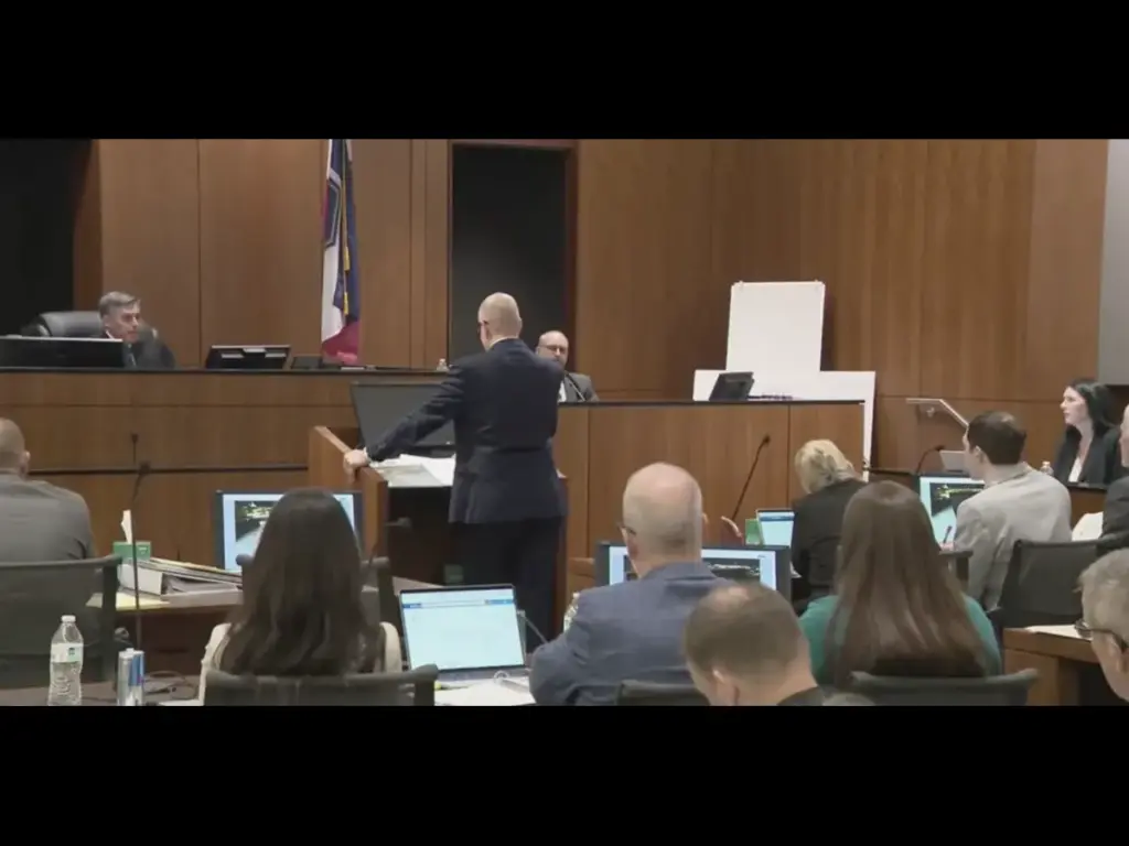 A wide shot of a courtroom for Tyler Robinson during a legal proceeding, showing a man in a suit standing and gesturing toward the front bench, as seen on a live television broadcast from KUTV 2 News.