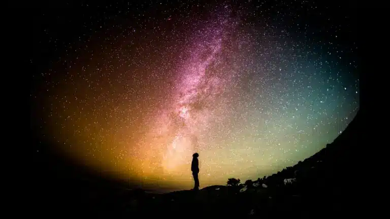 A silhouette of a man looking at stars in the universe.